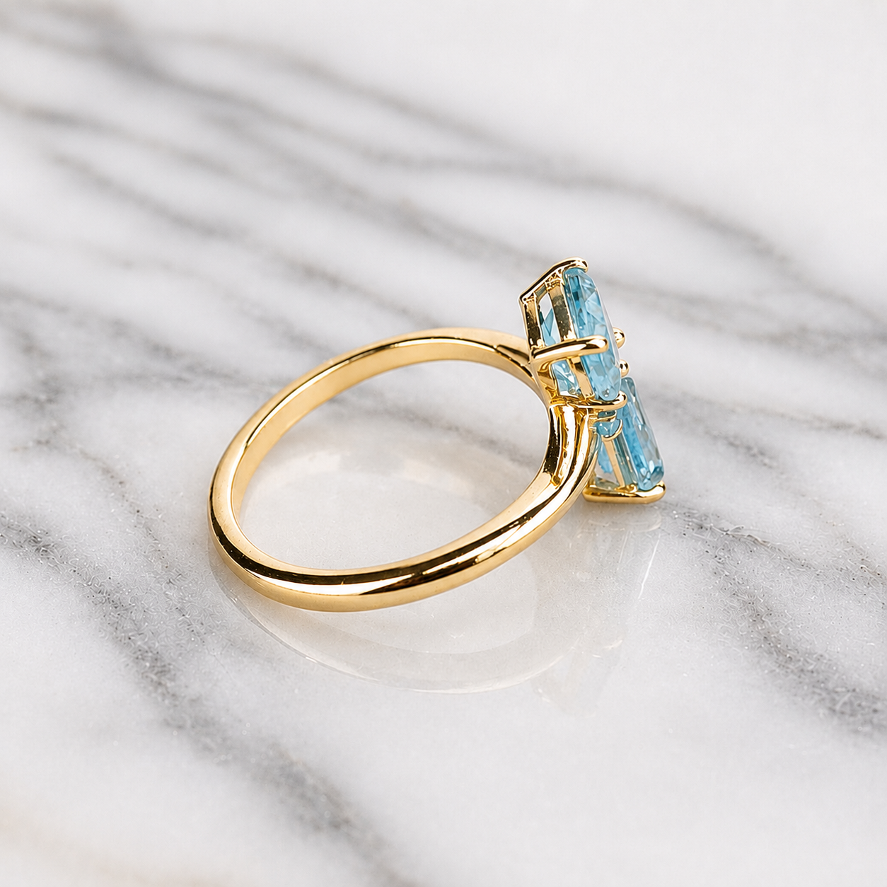 Gold ring with blue gemstones on a marble surface