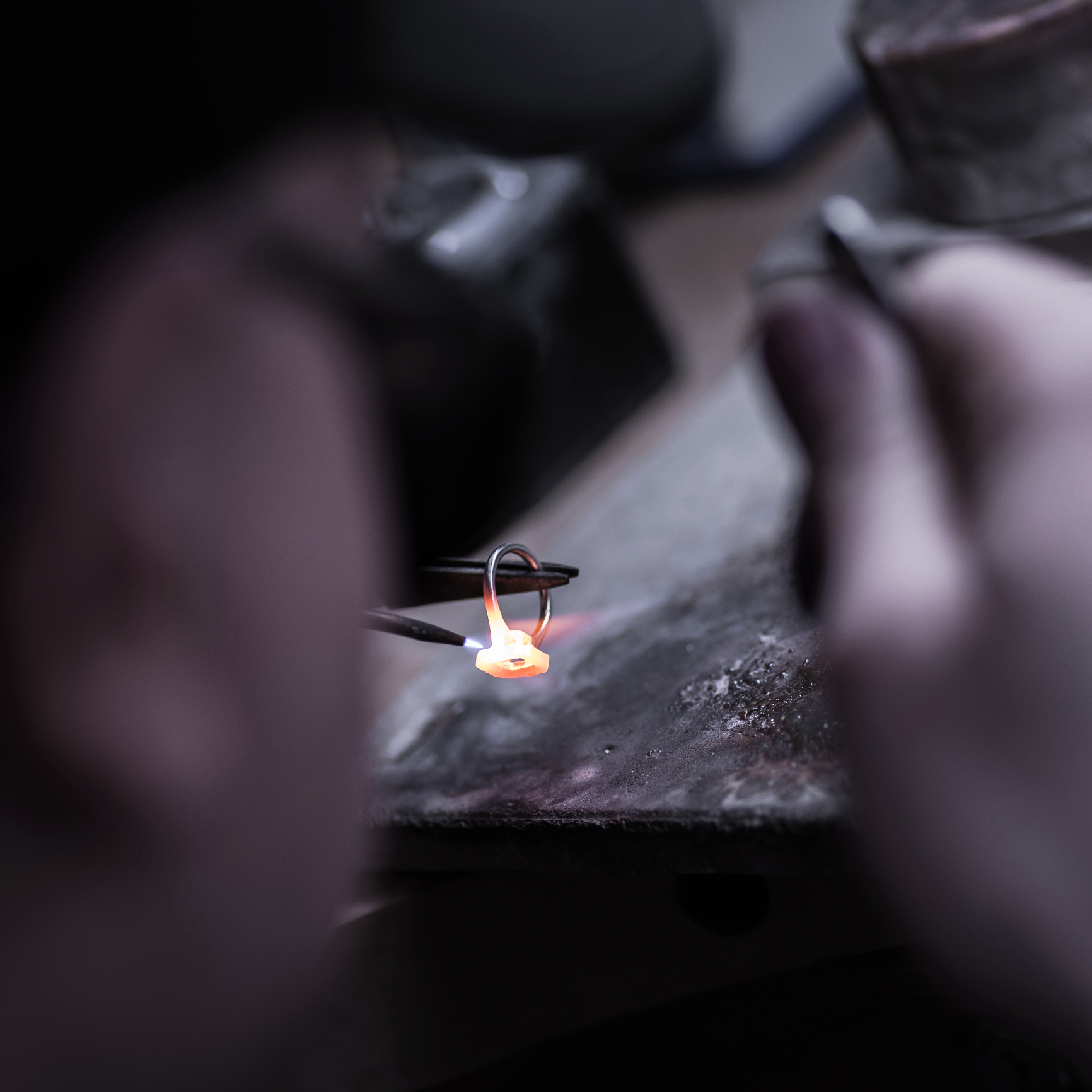 Close-up of hands working with a small flame on a dark background