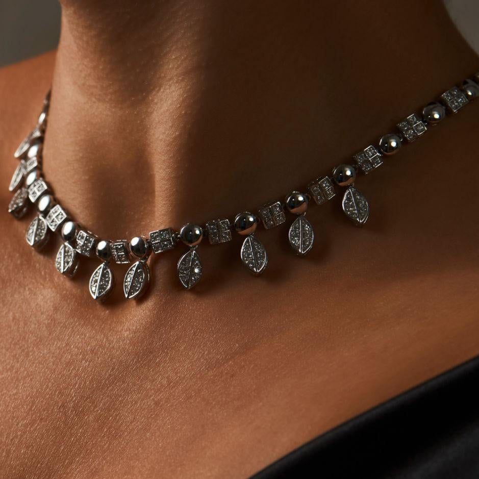 Necklace with black and silver stones on a person's neck against a neutral background