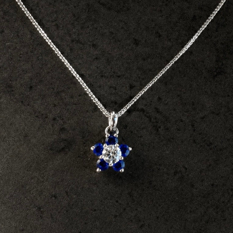 Silver necklace with a star-shaped pendant featuring blue stones on a black background