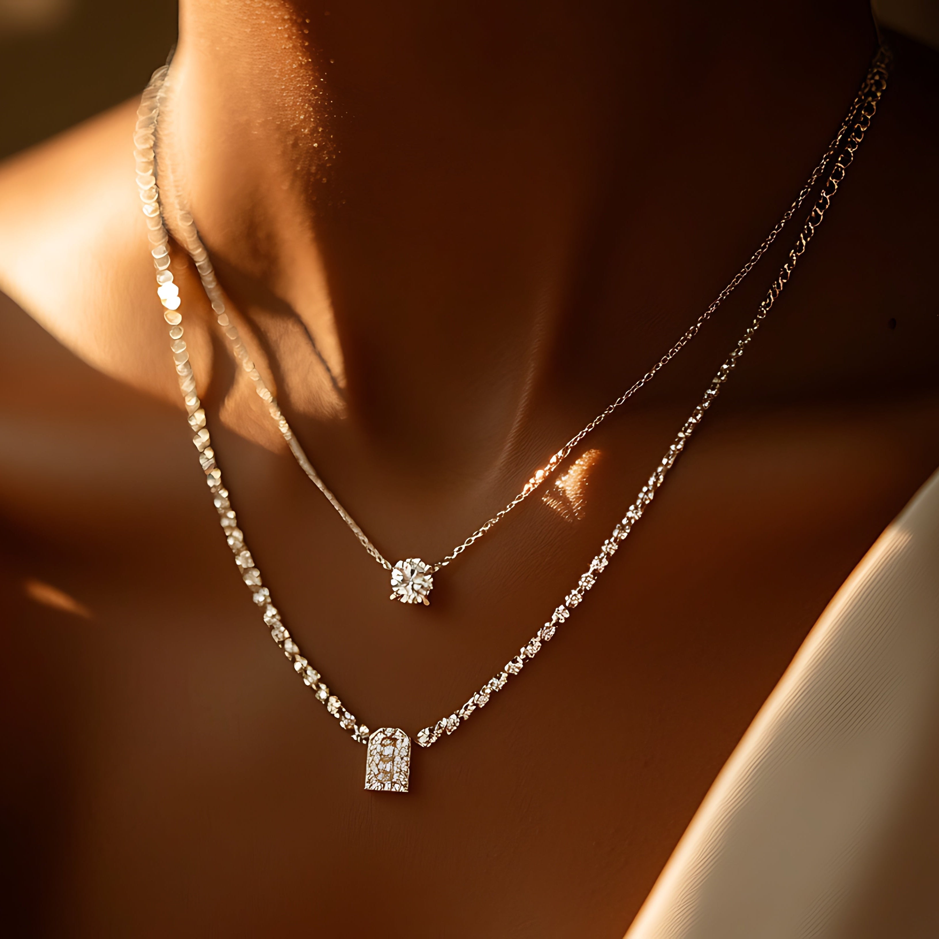 Close-up of a person wearing two diamond necklaces on a blurred background