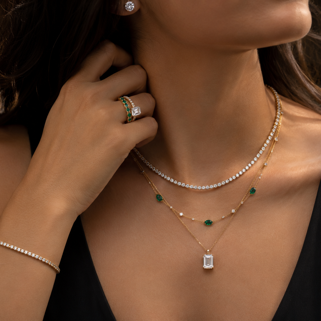 Close-up of a woman wearing multiple necklaces, rings, and a bracelet on a dark background.