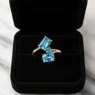 Gold ring with blue gemstones in a black jewelry box on a marble surface