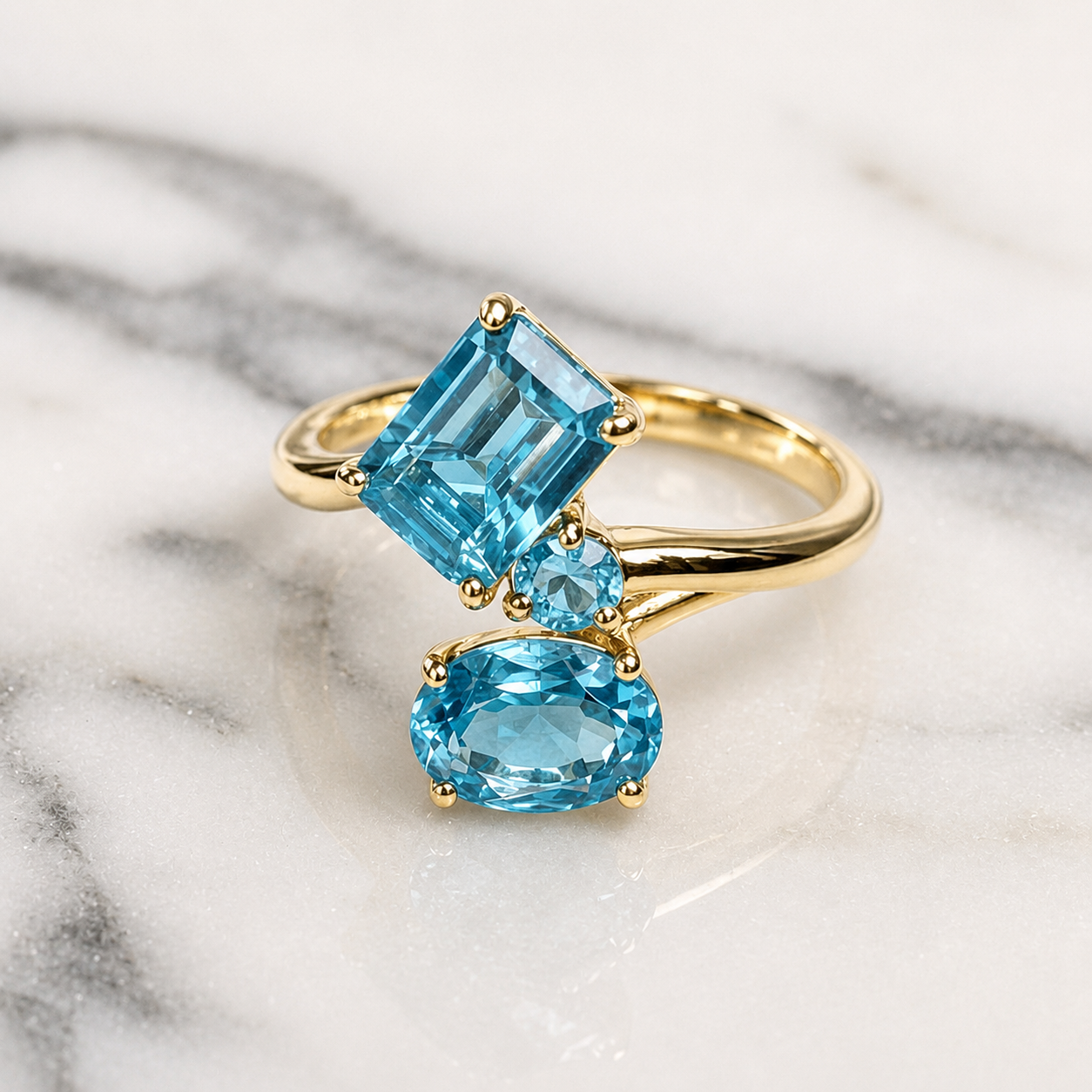 Gold ring with three blue gemstones on a marble surface