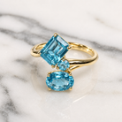 Gold ring with three blue gemstones on a marble surface