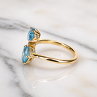 Gold ring with three blue gemstones on a marble surface
