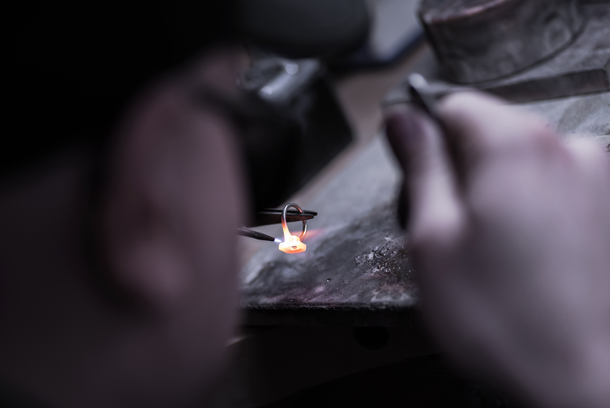 Close-up of hands working with a small flame on a dark background