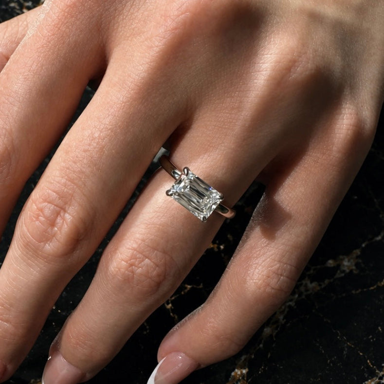 Hand wearing a diamond ring on a black marble surface