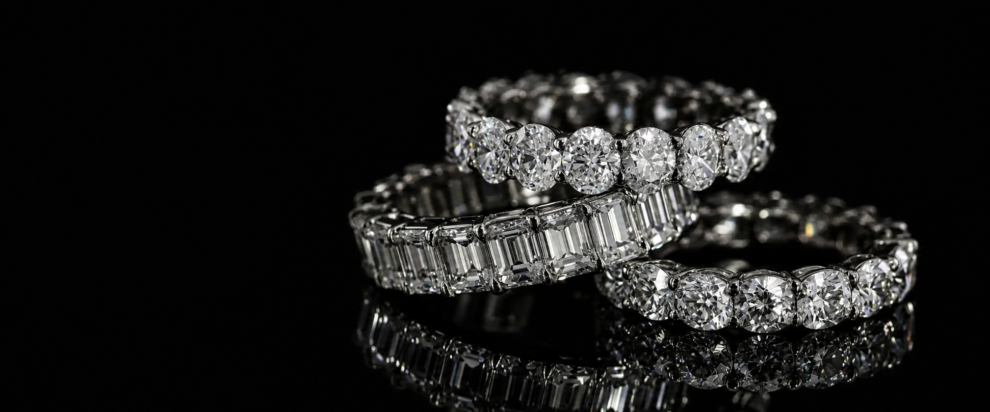 three diamond eternity rings stacked on a black background