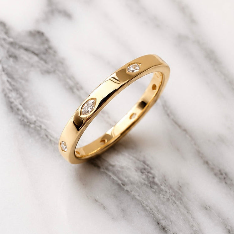 Gold ring with embedded diamonds on a marble surface