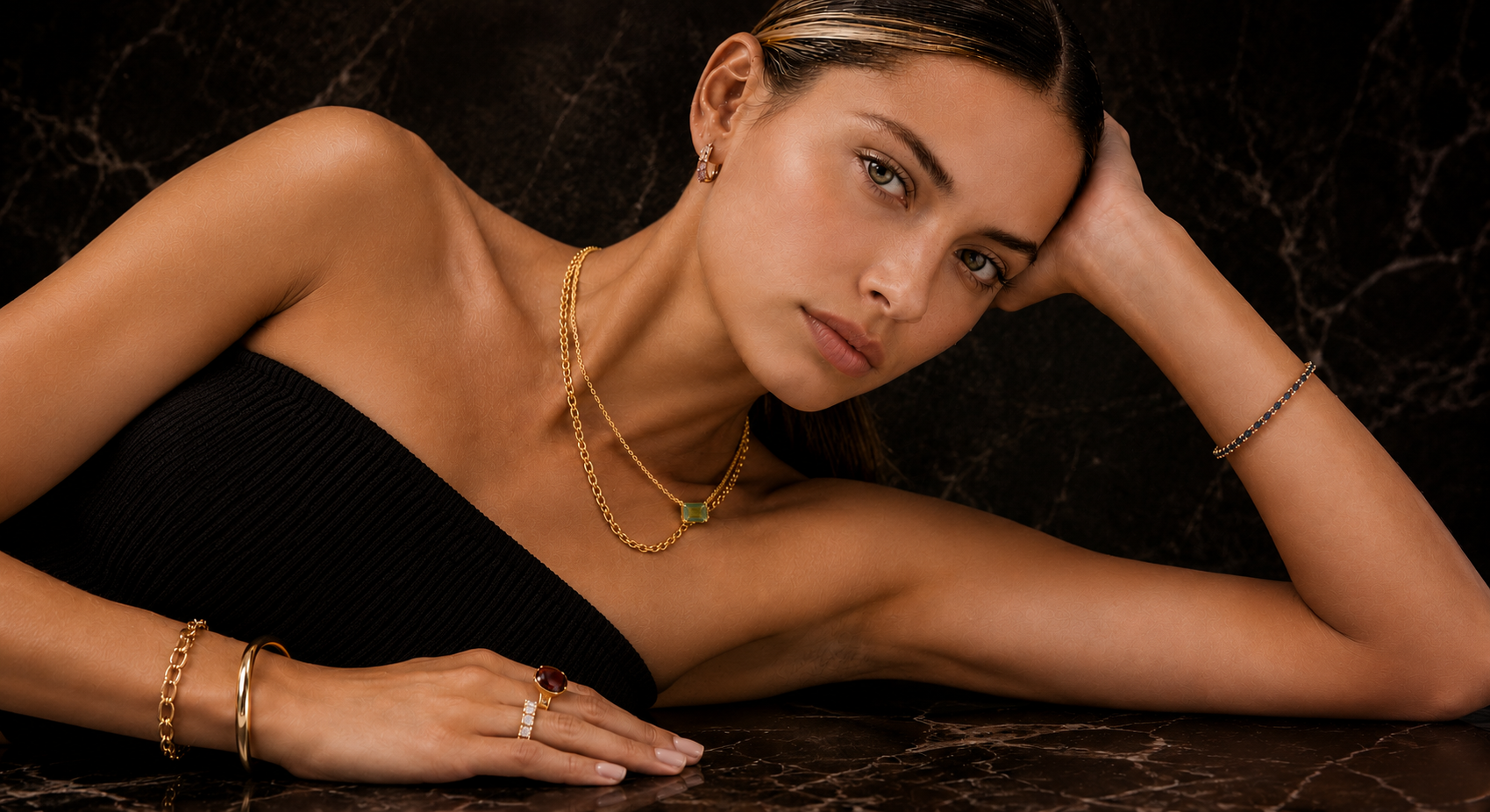 Woman wearing gold jewelry on a dark background