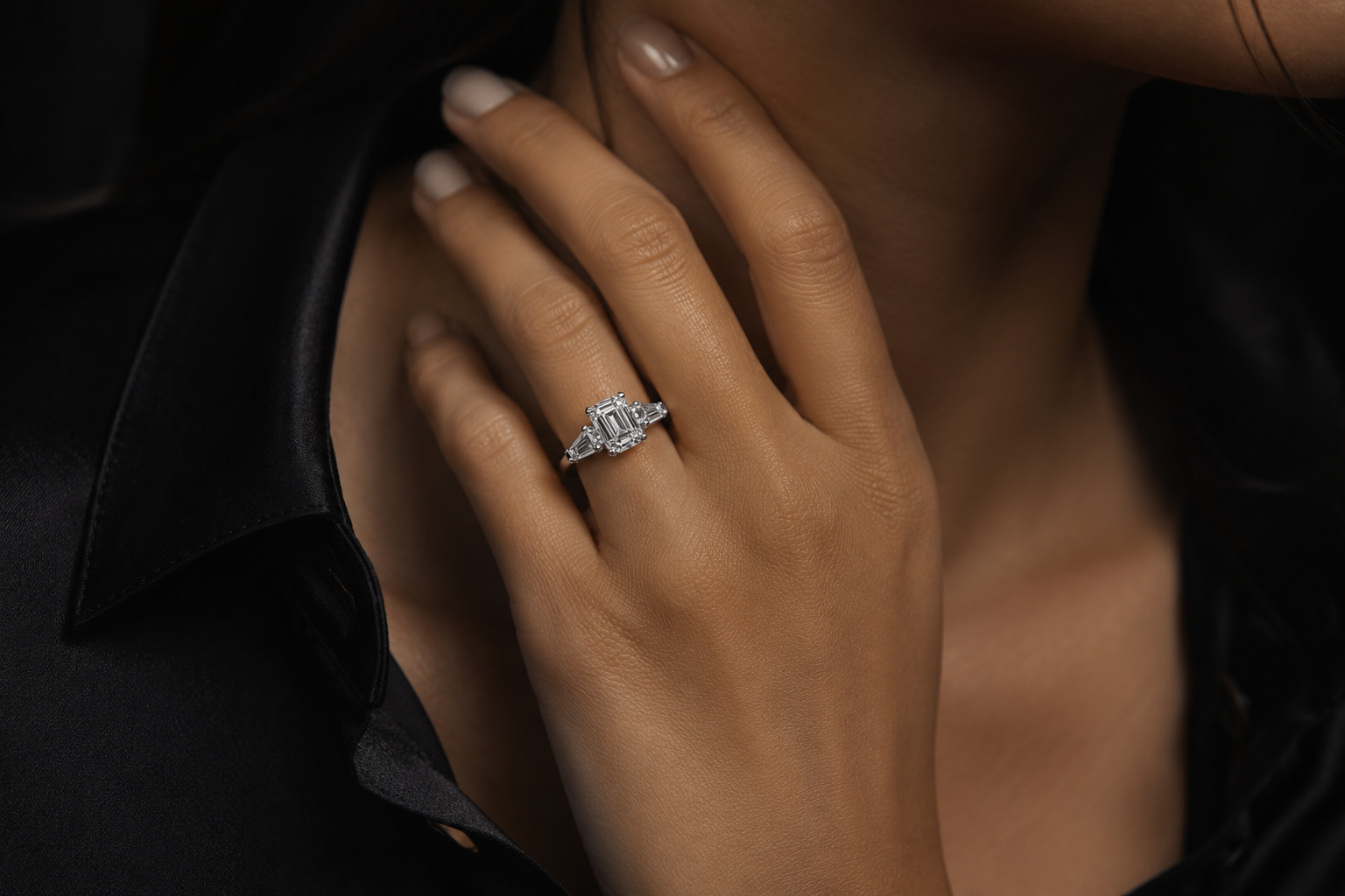 Close-up of a hand wearing a diamond ring with a dark background