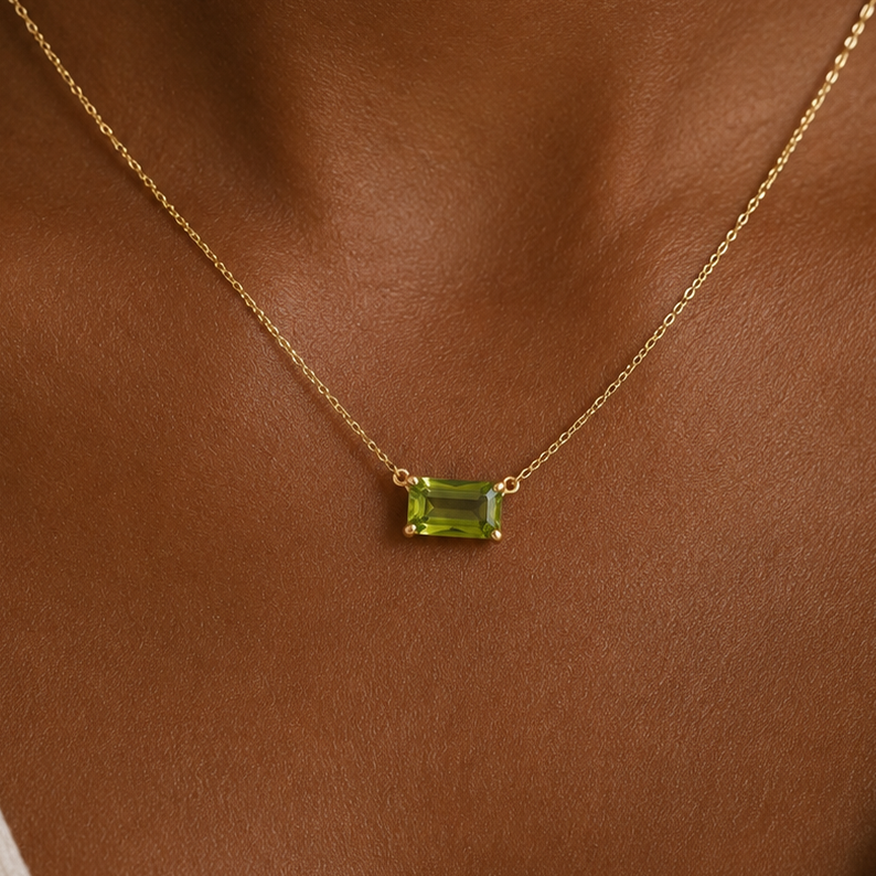 Gold necklace with a green gemstone on a brown background